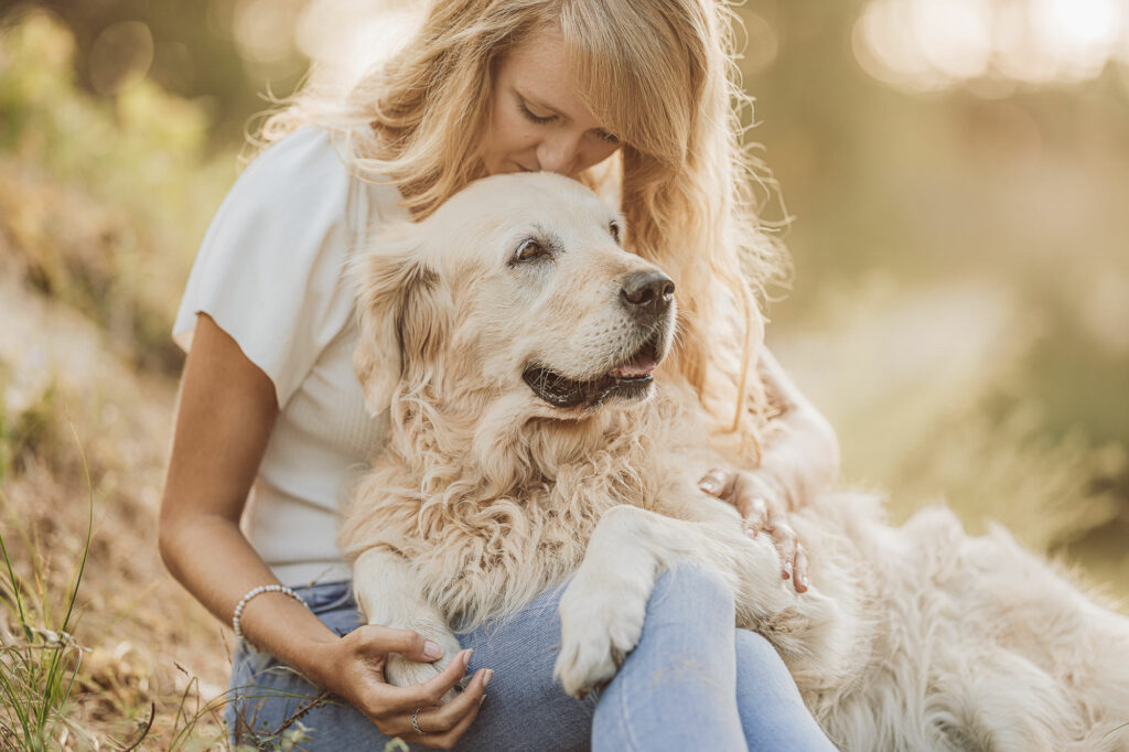 Junge Frau kuschelt mit Golden Retriever beim Fotoshooting am Strand