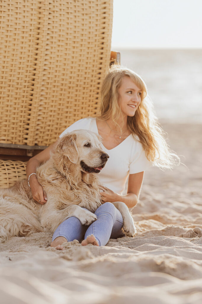 Junge Frau kuschelt mit Golden Retriever beim Fotoshooting am Strandkorb