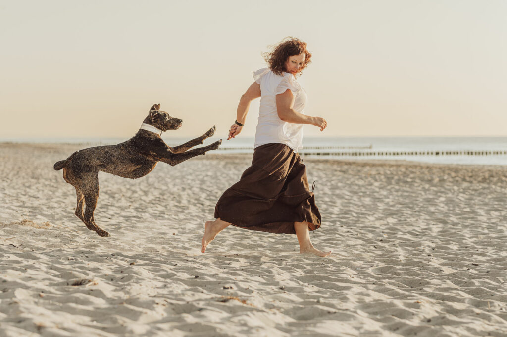 Catahoula spielt mit Frau am Strand beim Hundeshooting