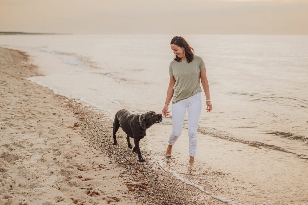 Frau mit Hund im Sonnenuntergang am Strand beim Hundeshooting