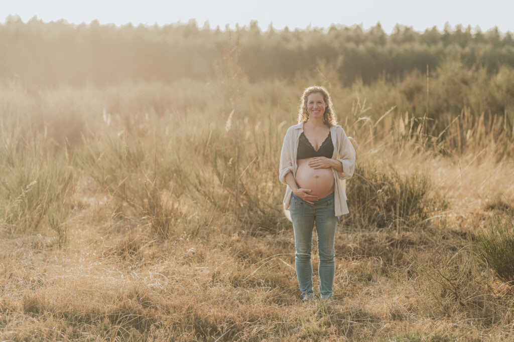 Babybauchfotos in der Natur – Julia hält liebevoll ihren Bauch