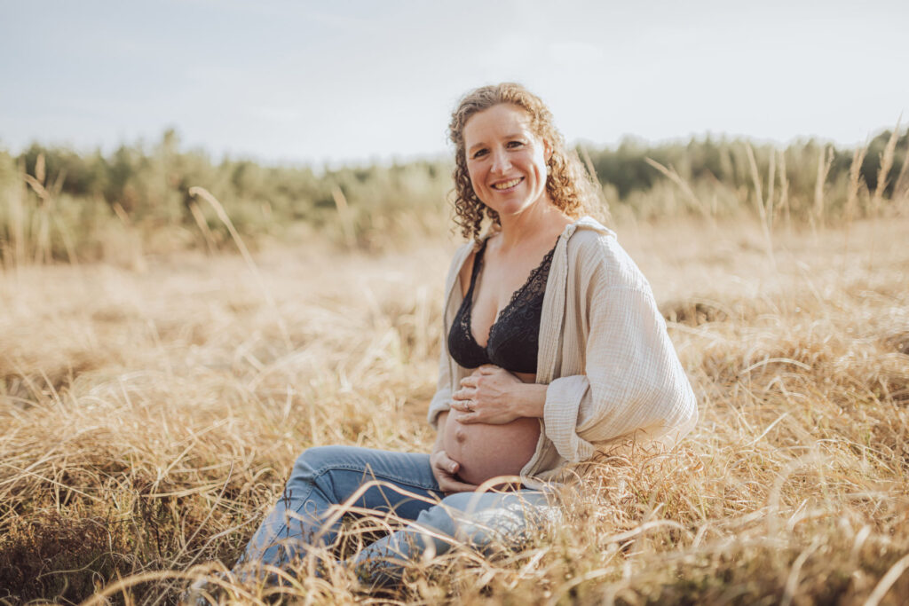 Babybauchfotos in der Natur – Julia hält liebevoll ihren Bauch
